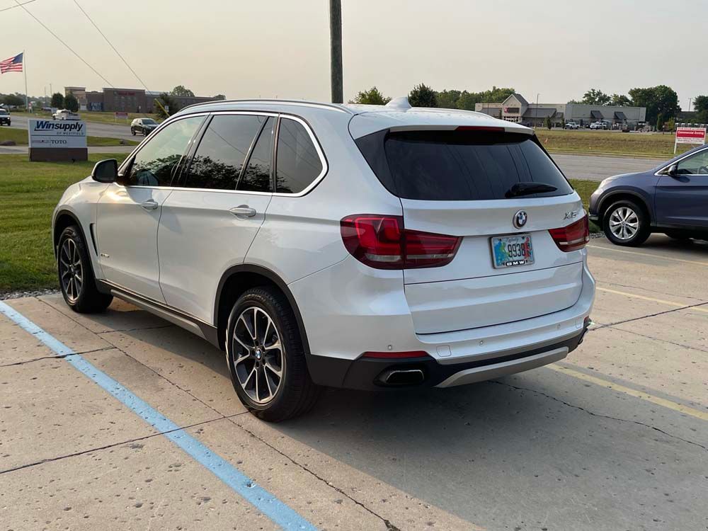 A white bmw x5 is parked in a parking lot.