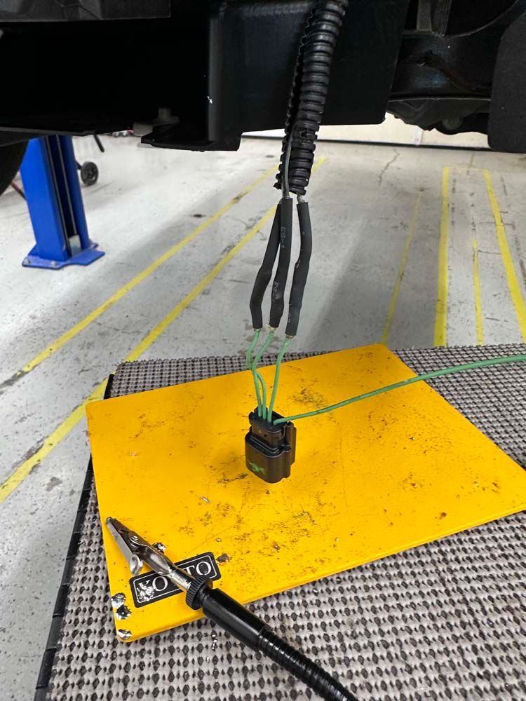 A hose is sitting on a yellow mat next to a pair of pliers.