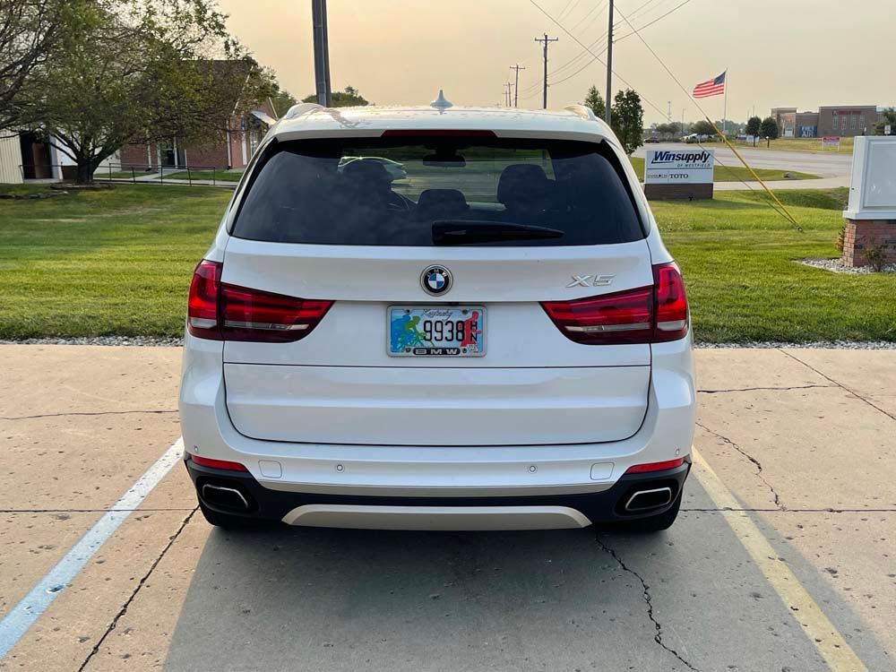 A white bmw x5 is parked in a parking lot.