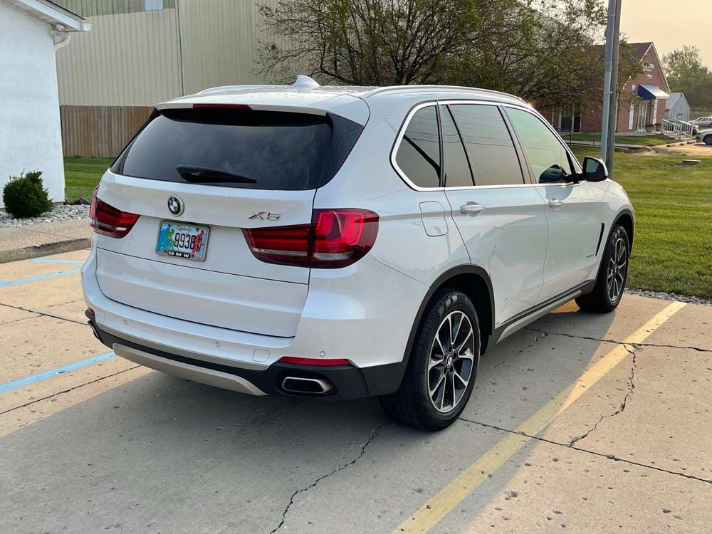 A white bmw x5 is parked in a parking lot.