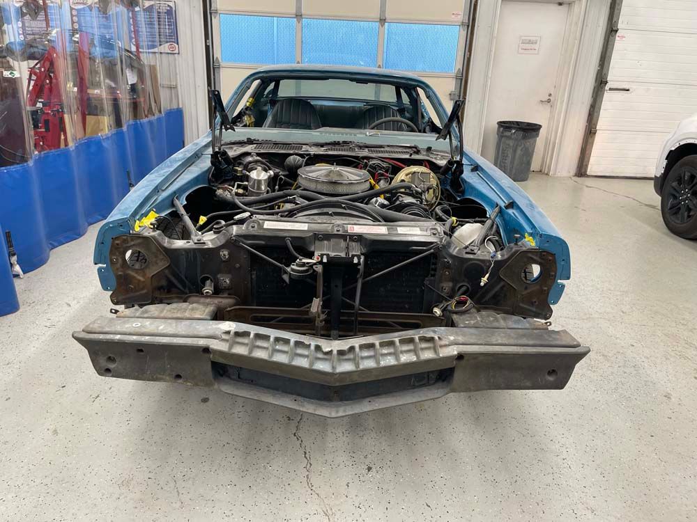 A blue car is being worked on in a garage.