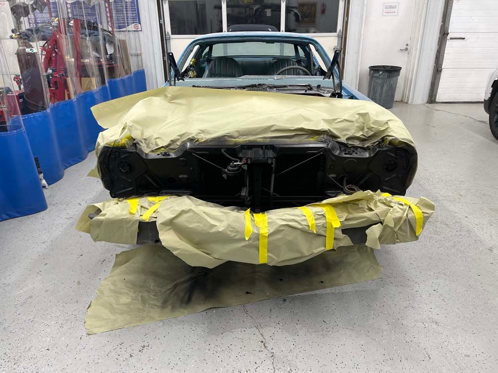 A car is wrapped in plastic and tape in a garage.