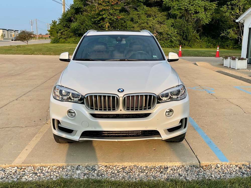 A white bmw x5 is parked in a parking lot.