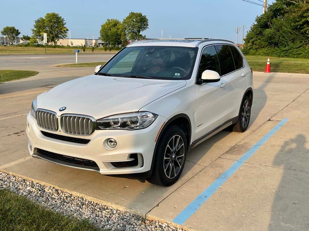 A white bmw x5 is parked in a parking lot.