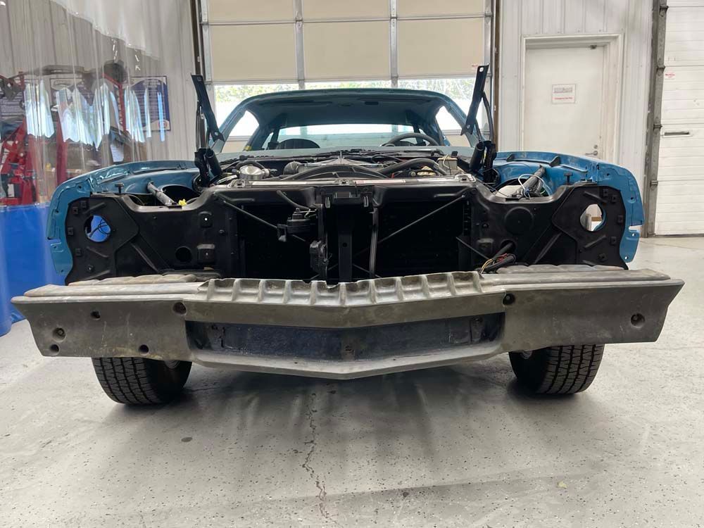 A blue car is being restored in a garage.