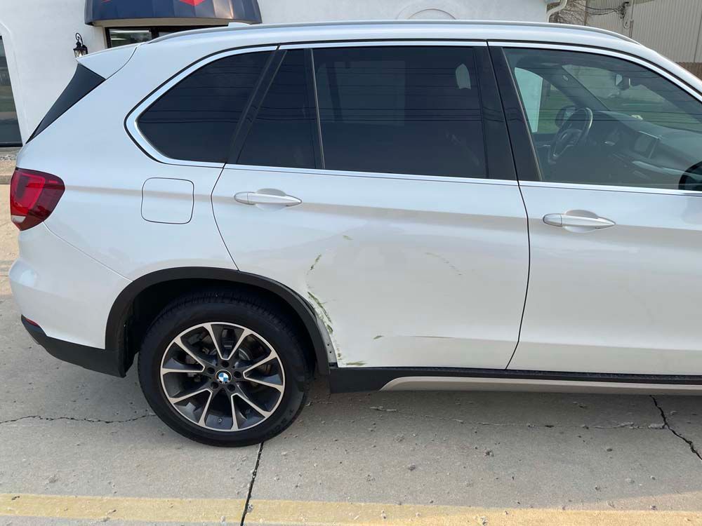 A white bmw x5 is parked in a parking lot.