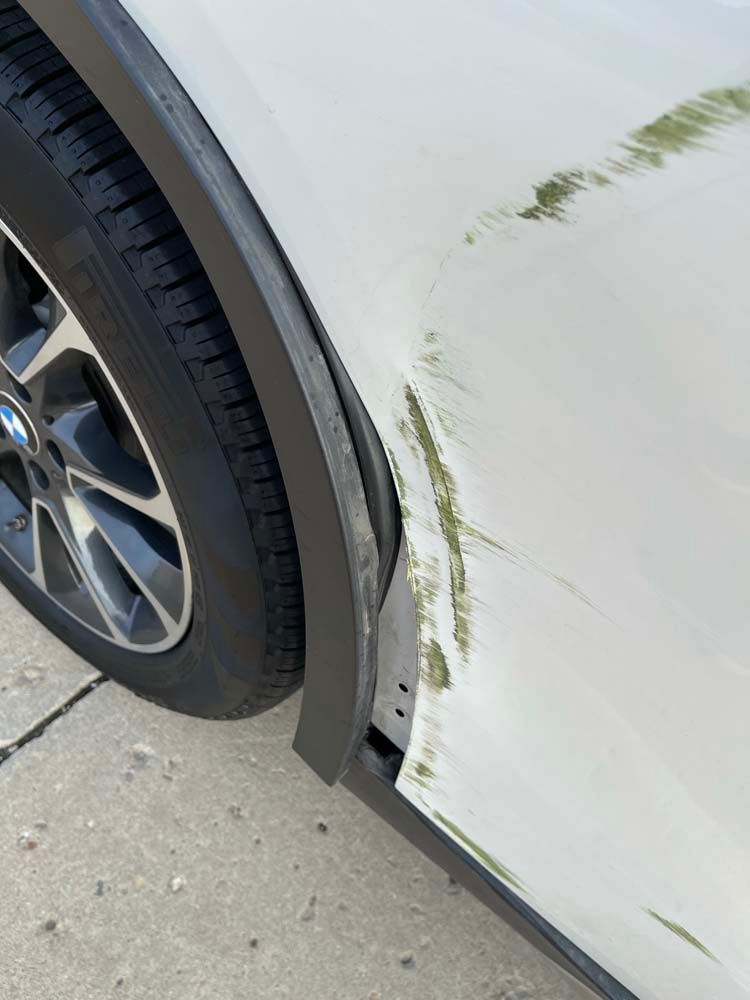 A white car with a scratch on the side of it.