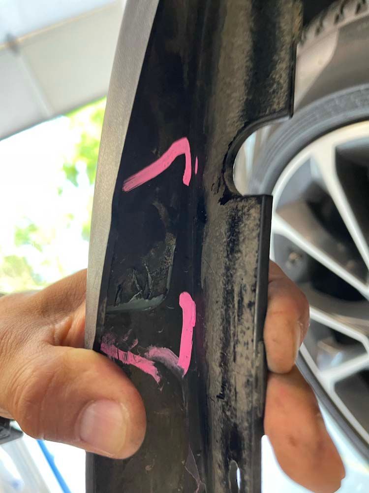 A person is holding a piece of metal with a pink sticker on it.