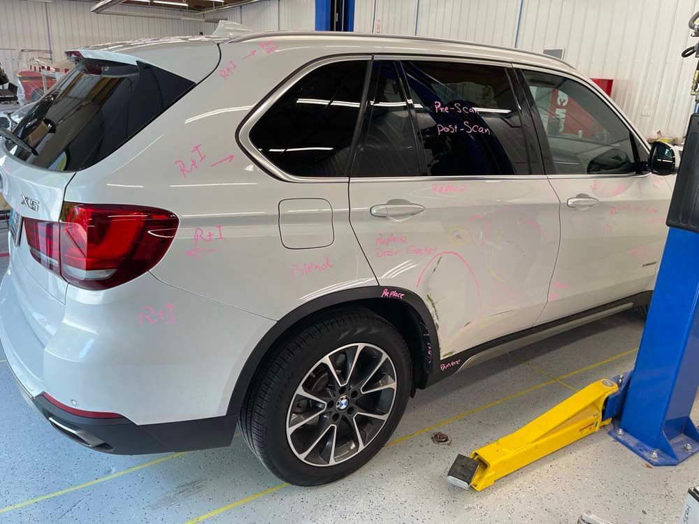 A white bmw x5 is parked on a lift in a garage.