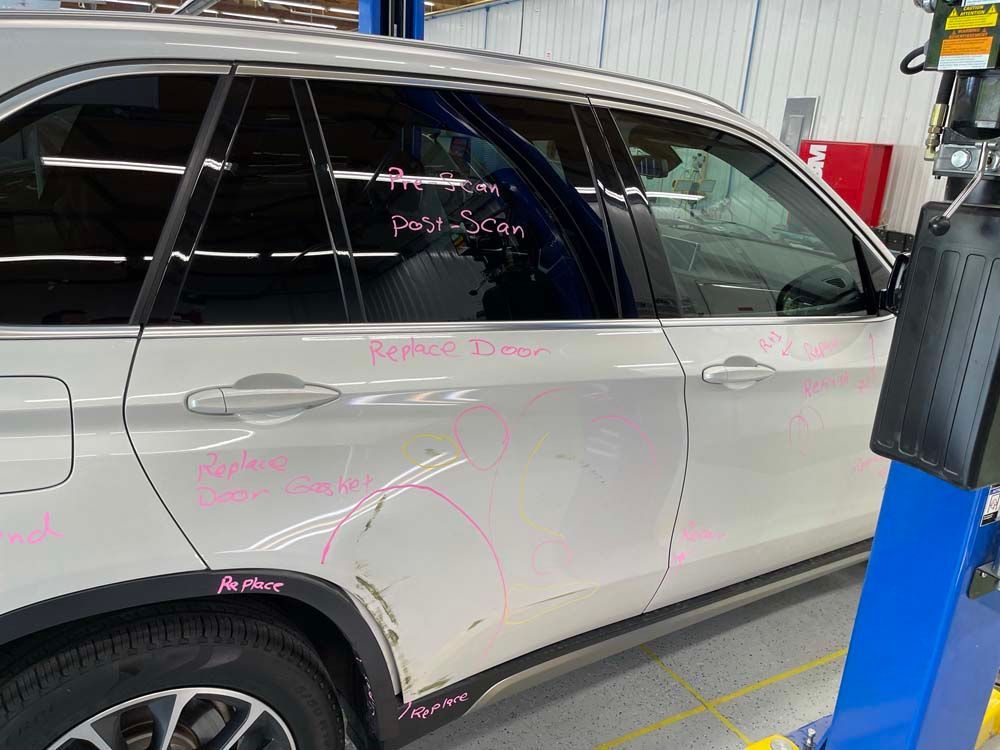 A white suv is sitting on top of a blue lift in a garage.
