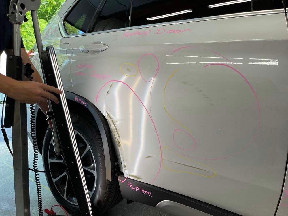 A person is working on the side of a car with a tool.