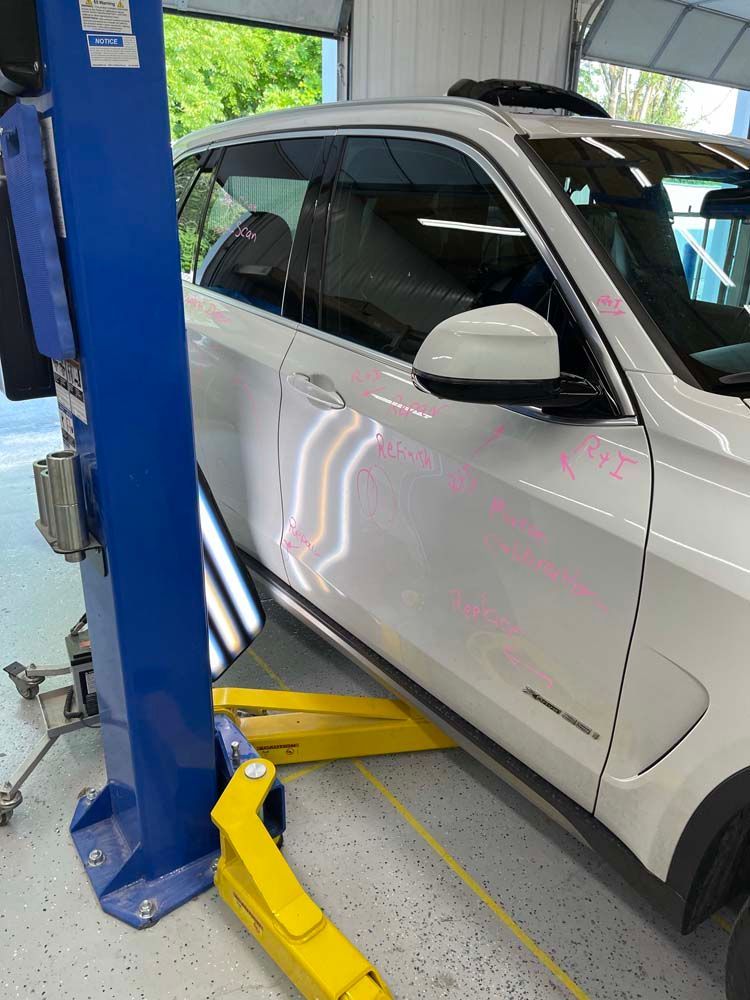 A white car is sitting on a lift in a garage.
