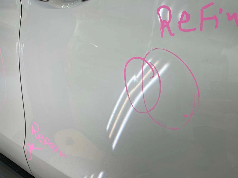 A close up of a white car door with a pink circle drawn on it.