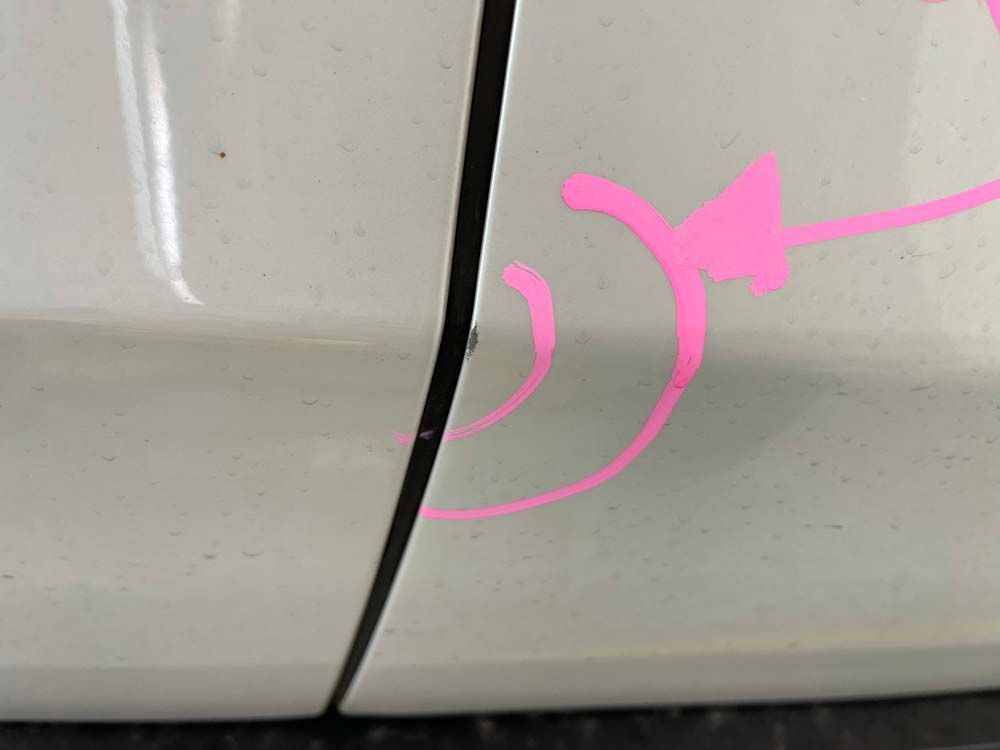 A close up of a white car with a pink arrow on it.