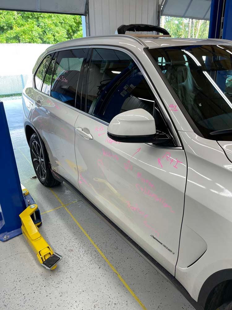 A white car is parked on a lift in a garage.