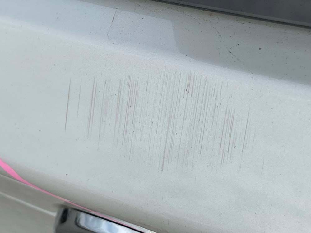 A close up of a scratch on the side of a car.