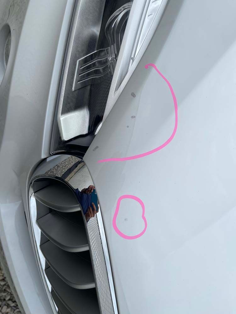 A close up of a white car with a pink circle drawn on it.