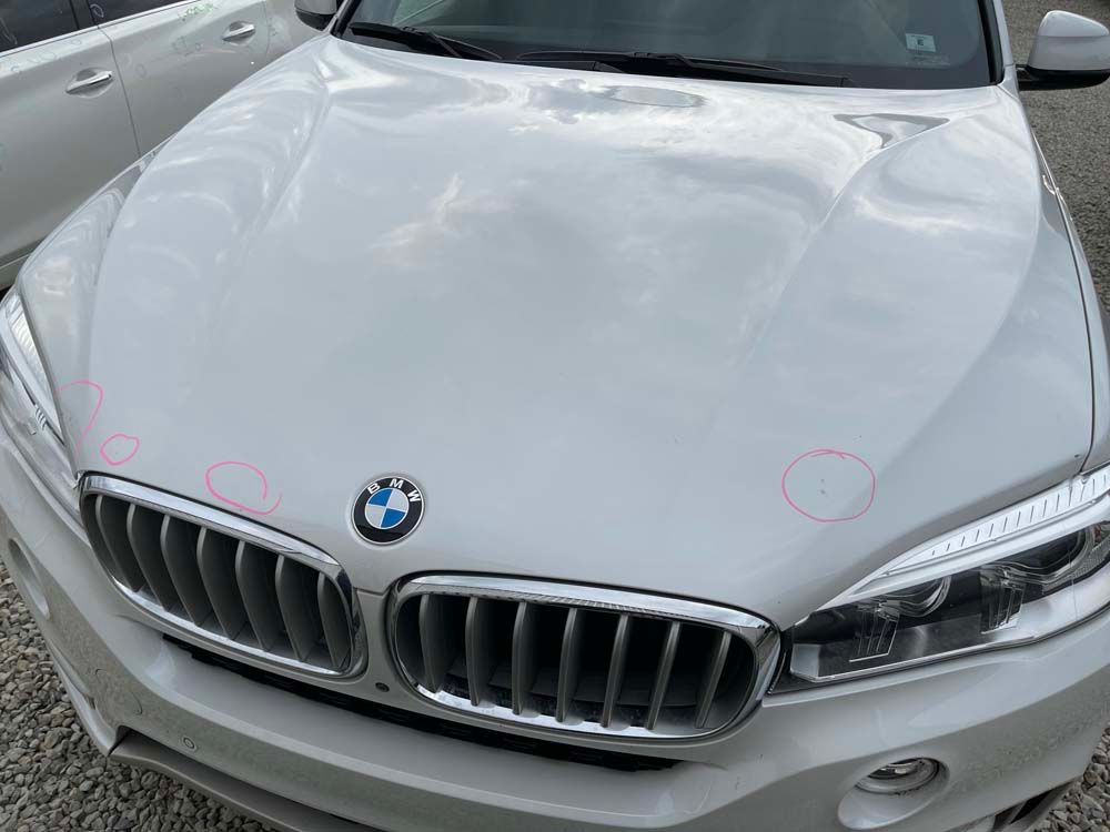 A white bmw x5 is parked in a parking lot.
