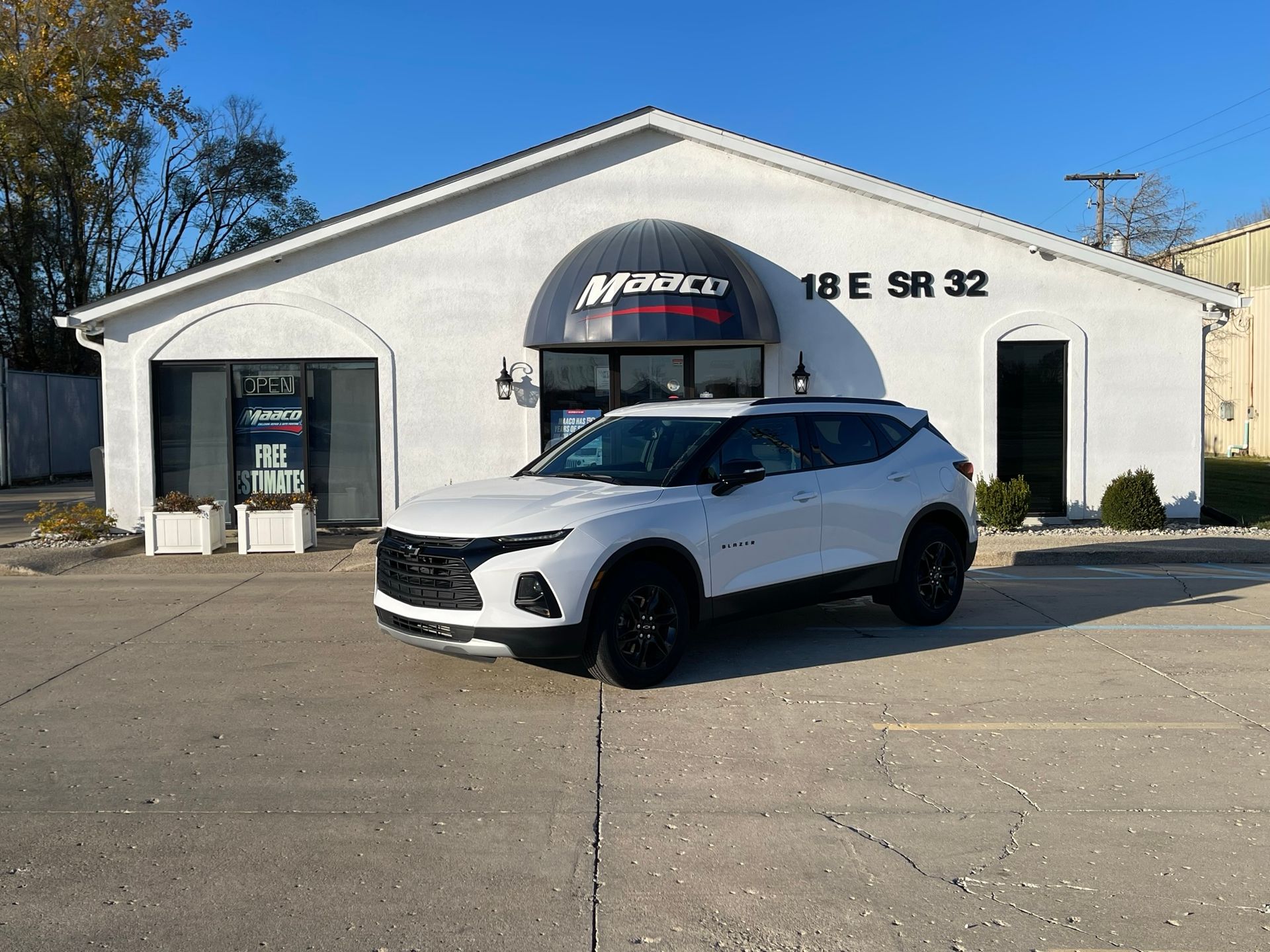 A white chevrolet blazer is parked in front of a white building.