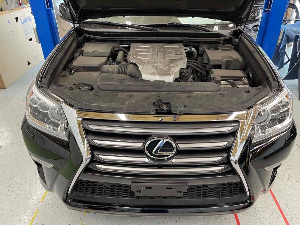 The hood of a black lexus is open in a garage.