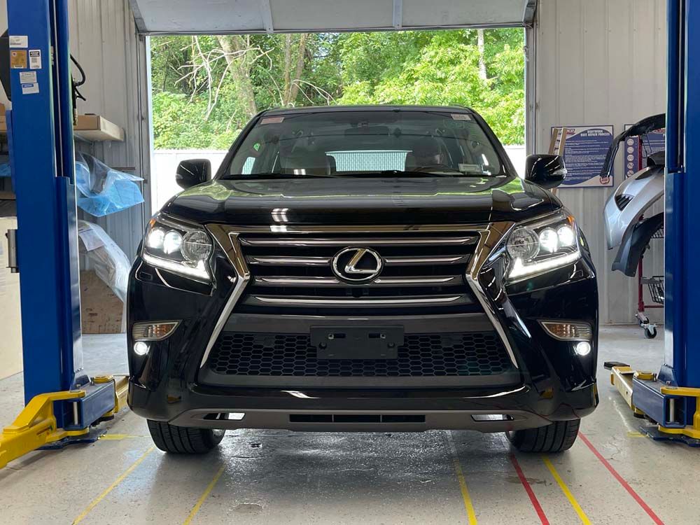 A black lexus is parked in a garage on a lift.