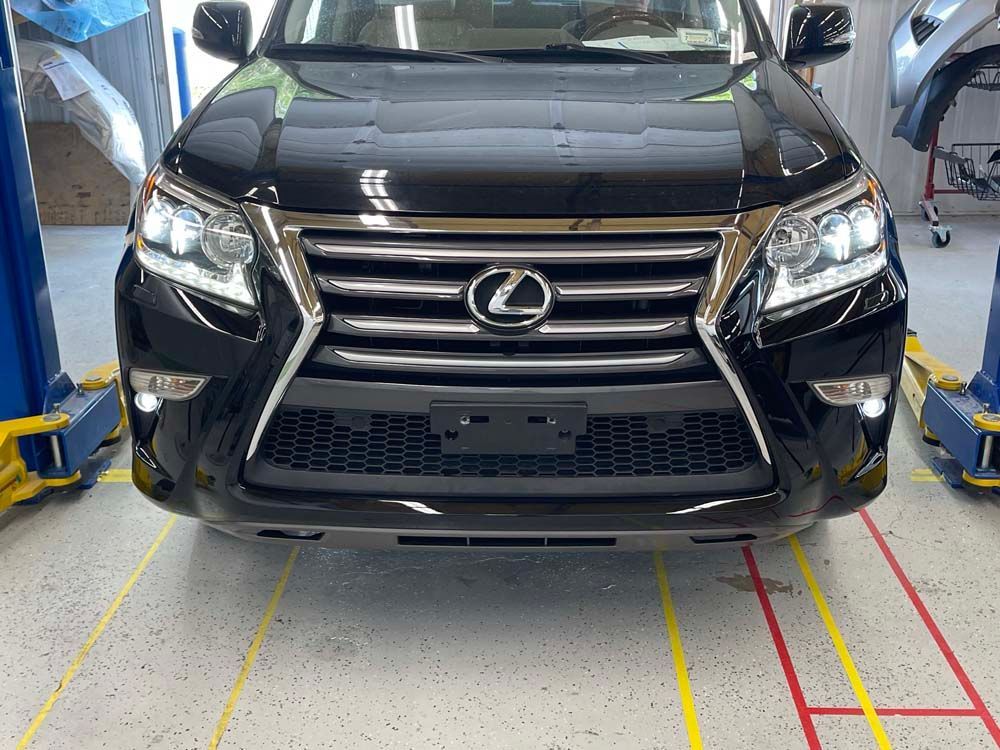 A black lexus is parked on a lift in a garage.