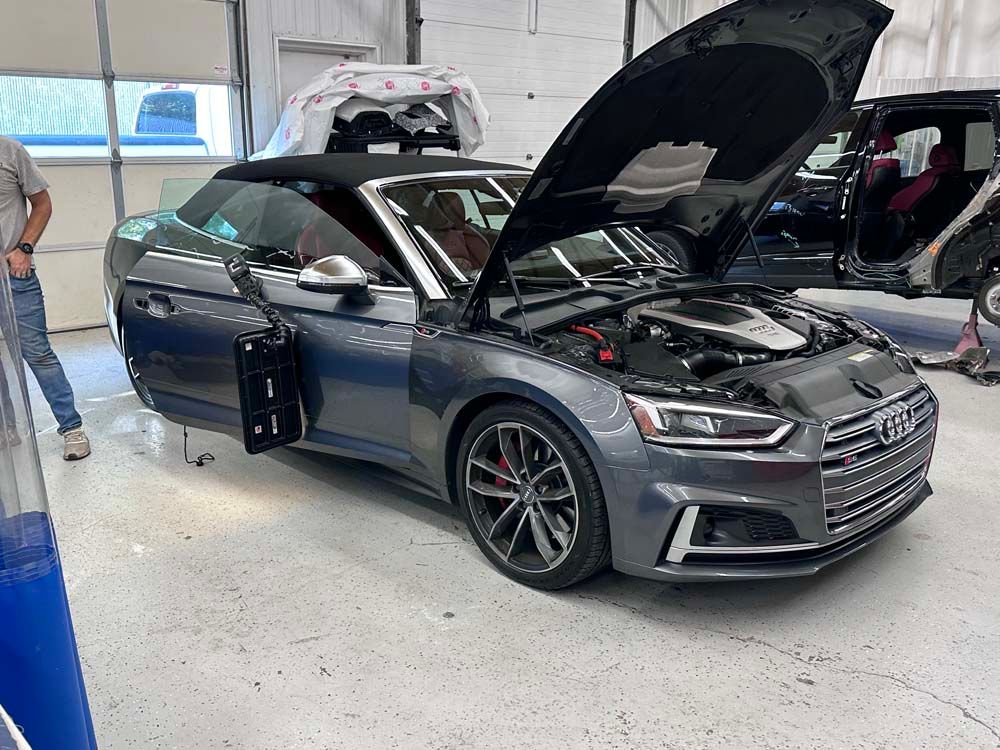 A gray audi a5 convertible with the hood up in a garage.