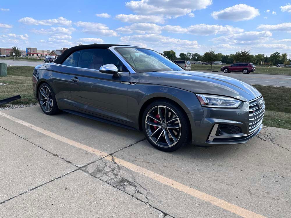A gray audi a5 convertible is parked on the side of the road.