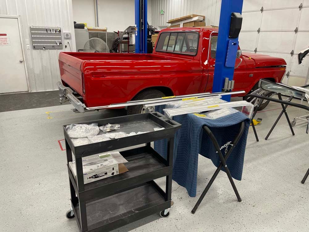 A red truck is parked in a garage next to a black cart.