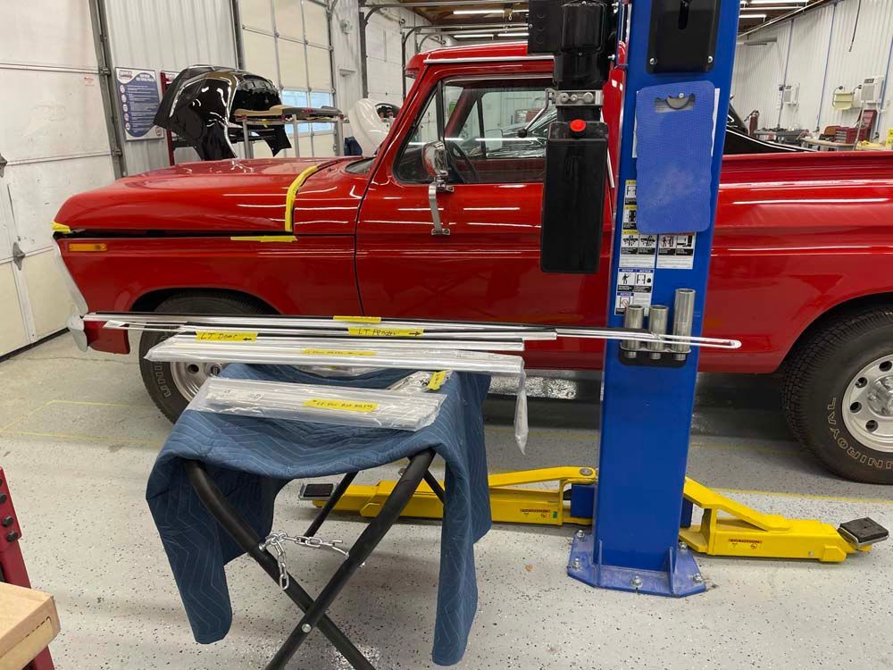 A red truck is sitting on a lift in a garage.