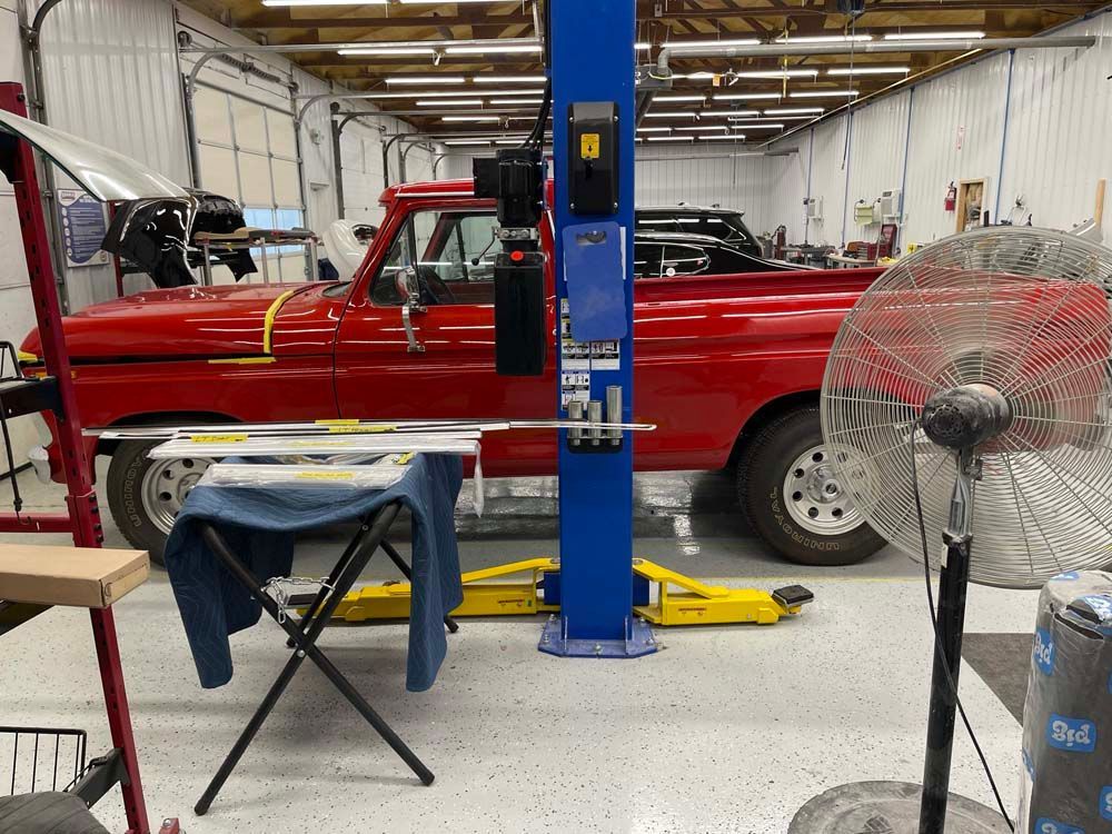 A red truck is on a lift in a garage.