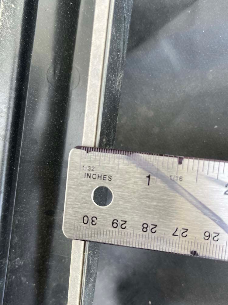 A ruler is being used to measure a window frame
