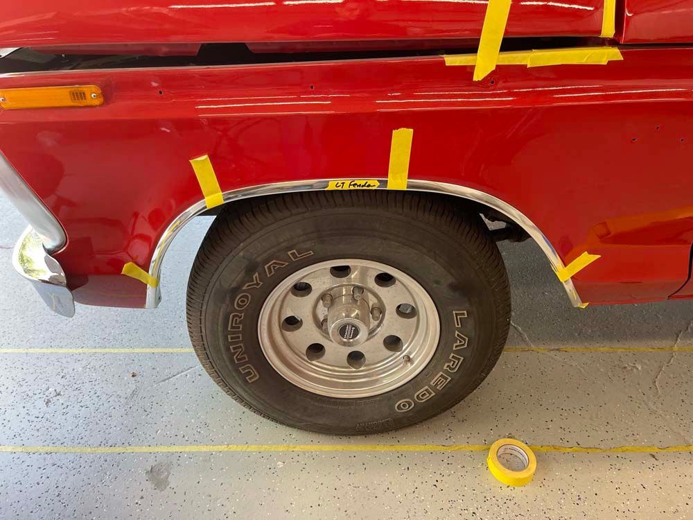 A red truck with yellow tape on the fenders