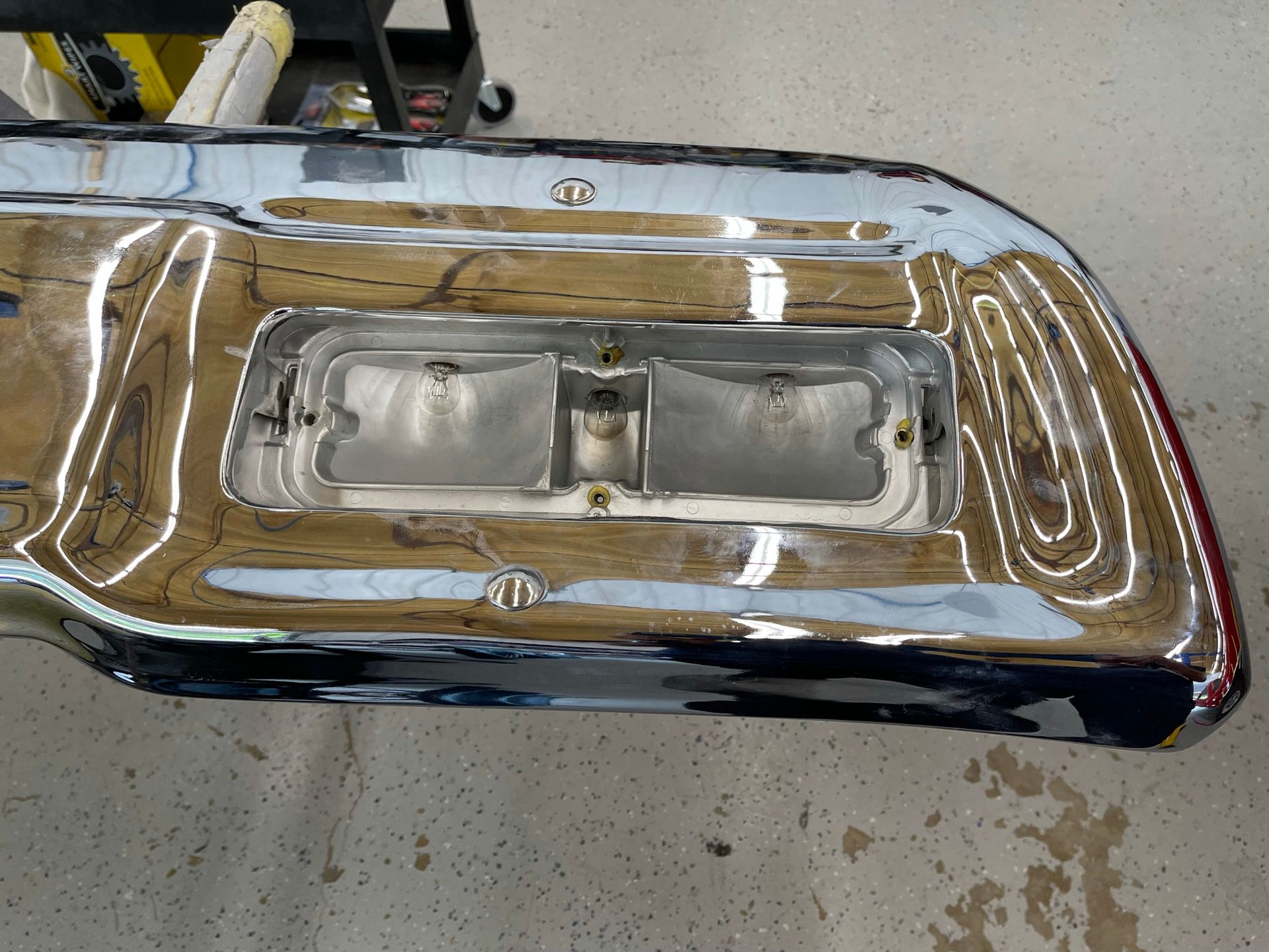 A chrome bumper is sitting on a concrete floor