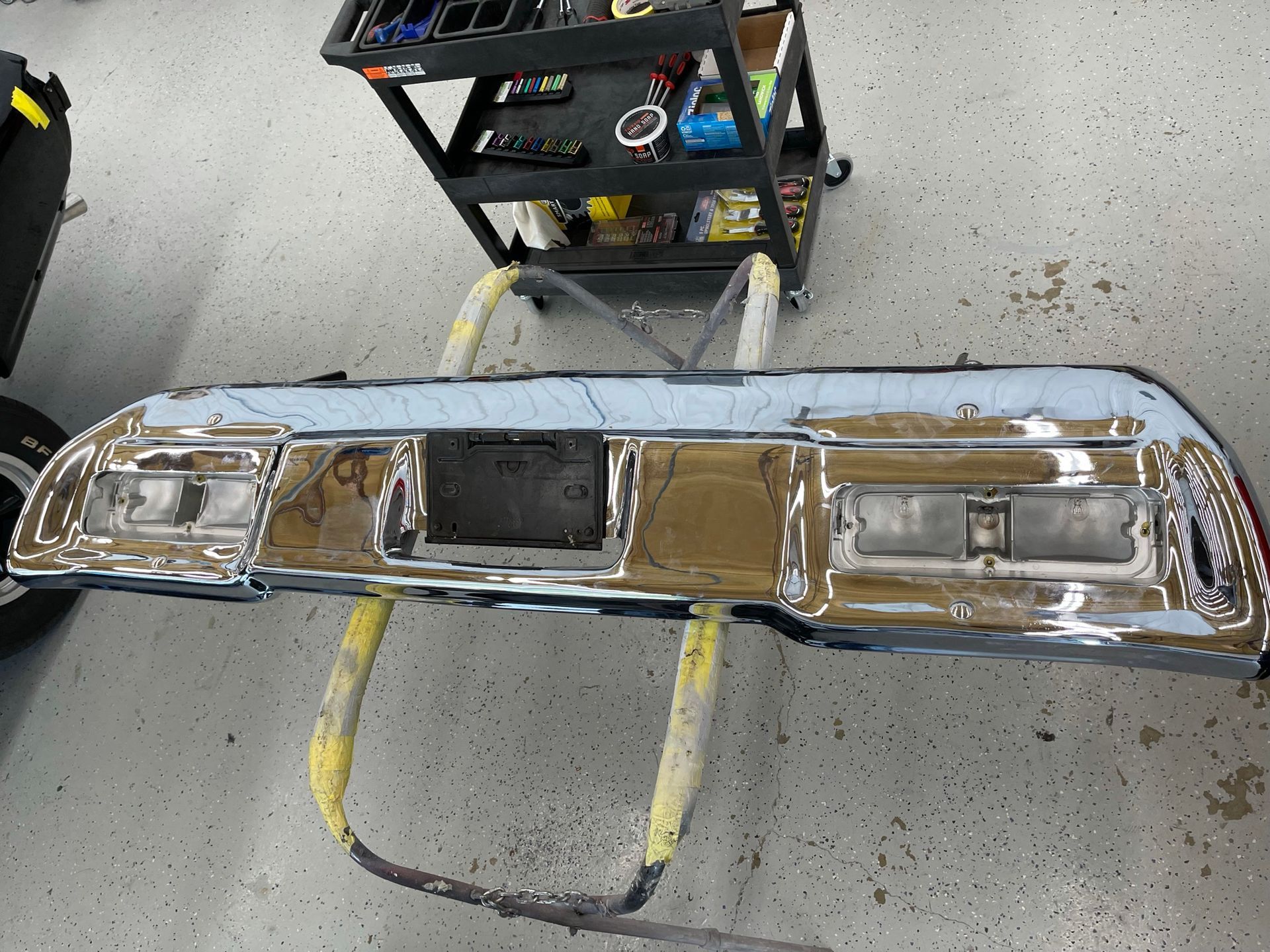 A chrome bumper is sitting on a stand in a garage