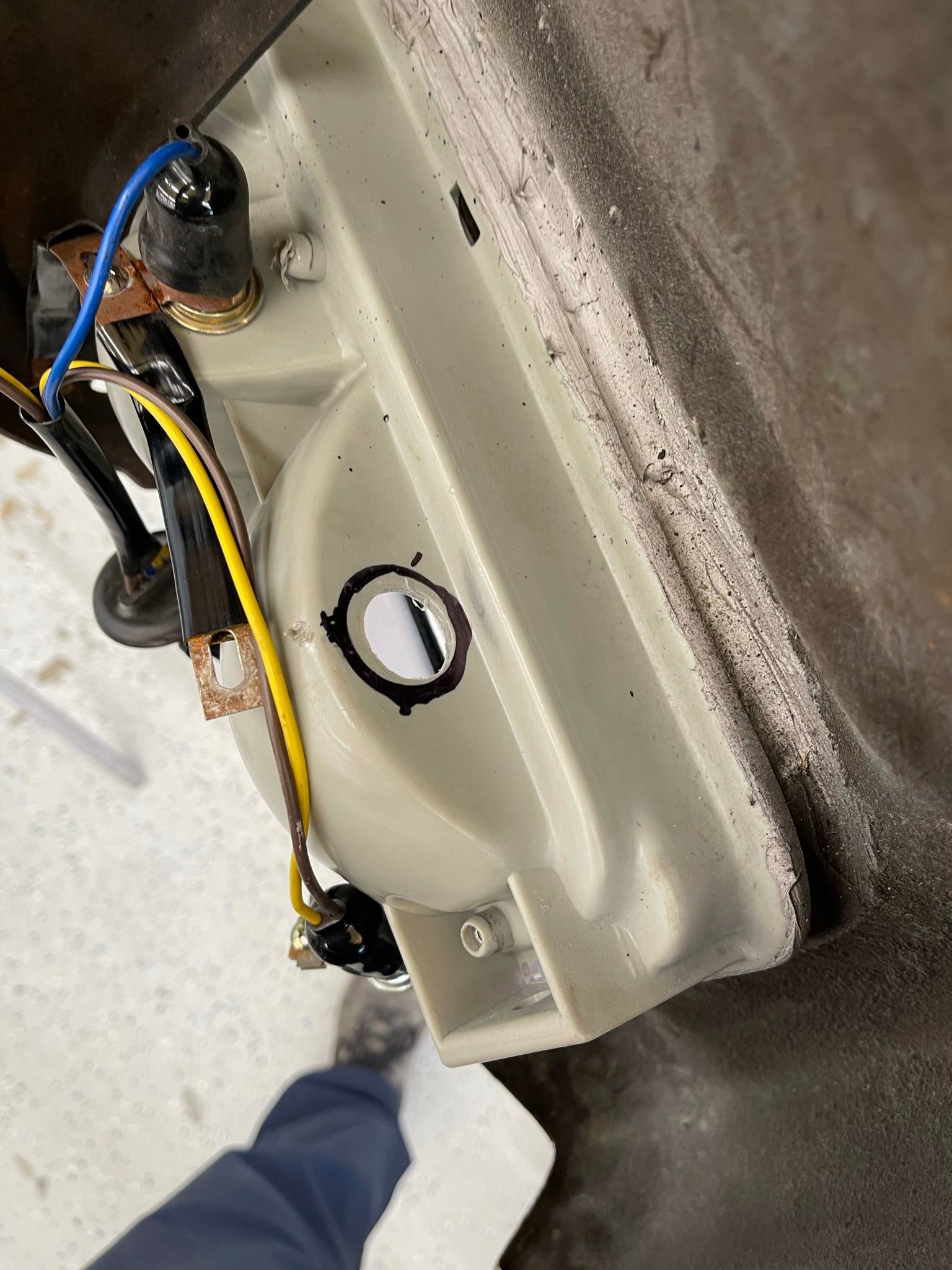 A person is standing next to a sink with wires coming out of it.