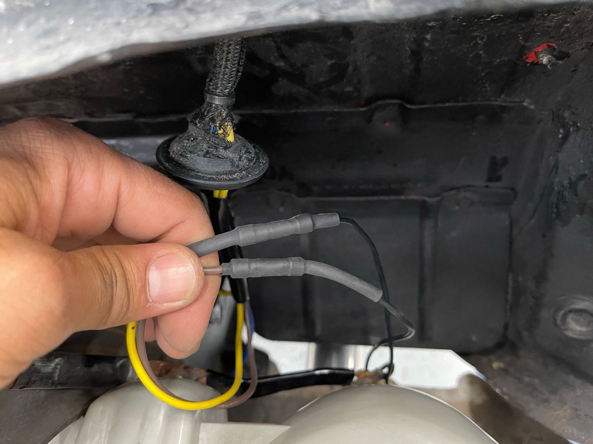 A person is holding a wire in their hand in front of a car.