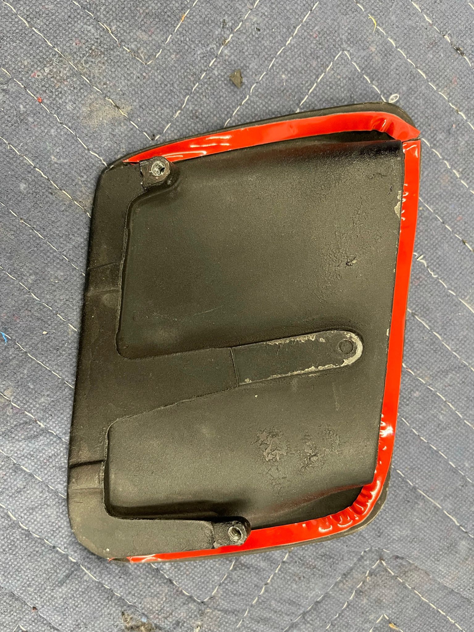 A black object with a red border is sitting on a blue surface.