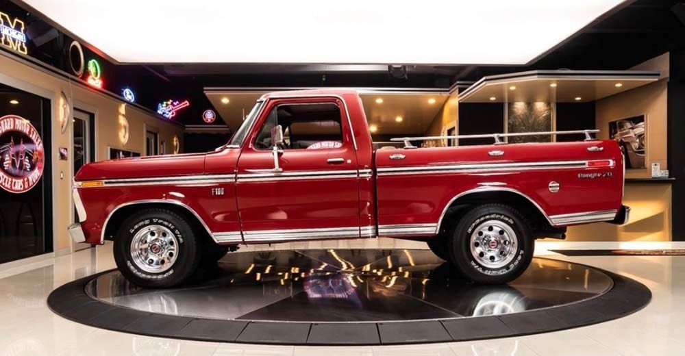 A red pickup truck is parked on a circular display in a garage.