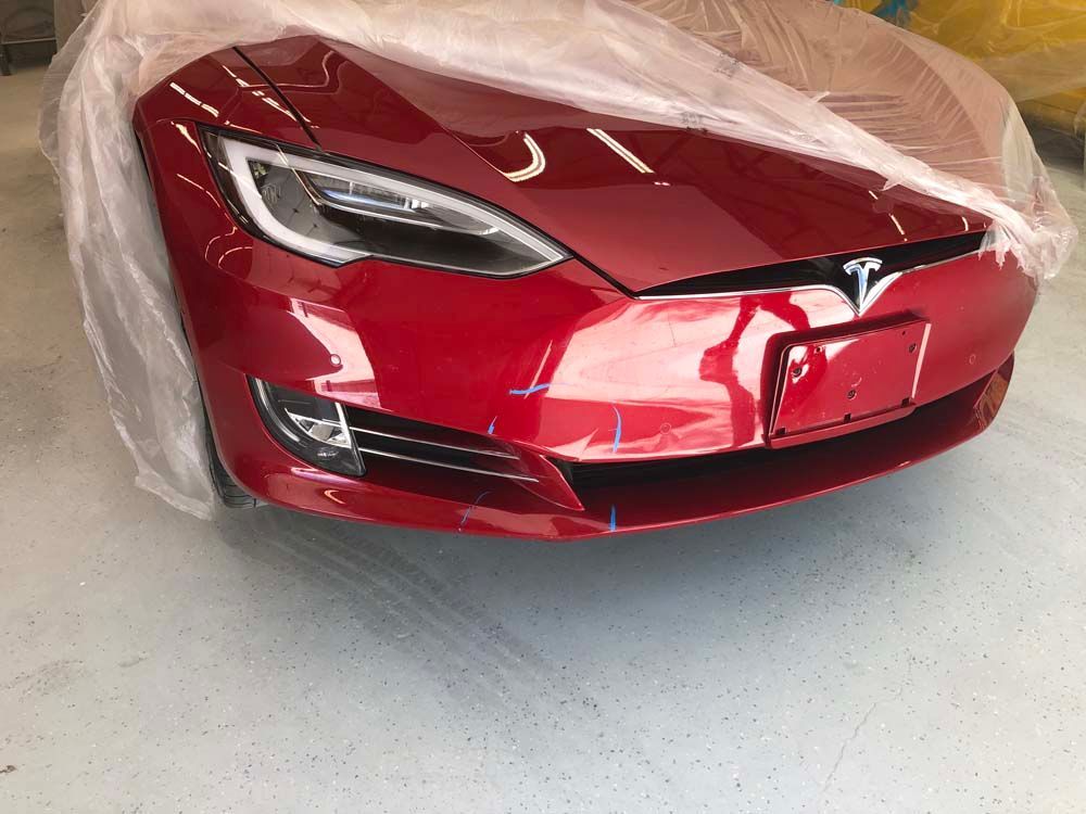 A red tesla model s is wrapped in plastic