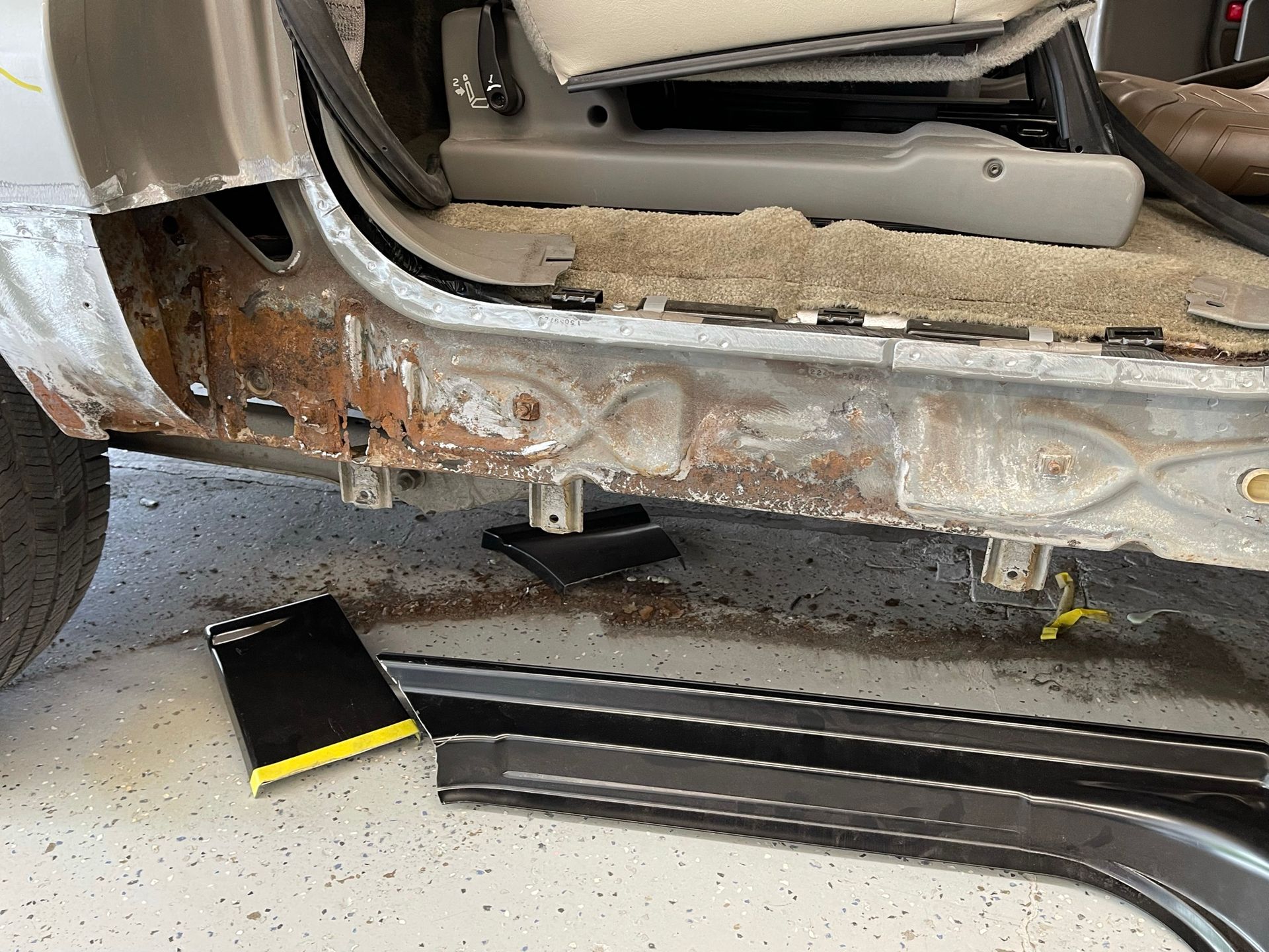 The side of a car is being repaired in a garage.