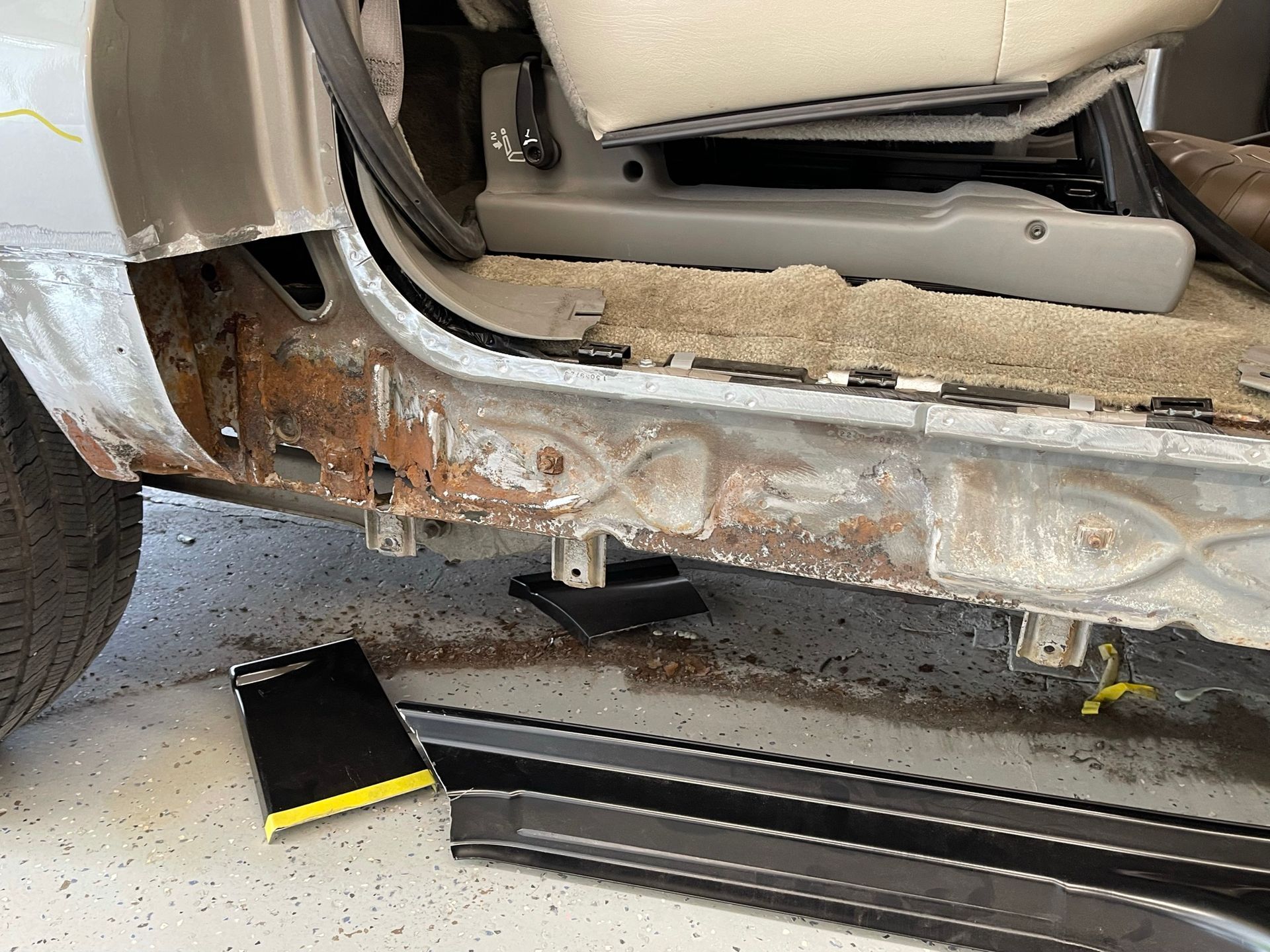 The side of a car is being repaired in a garage.