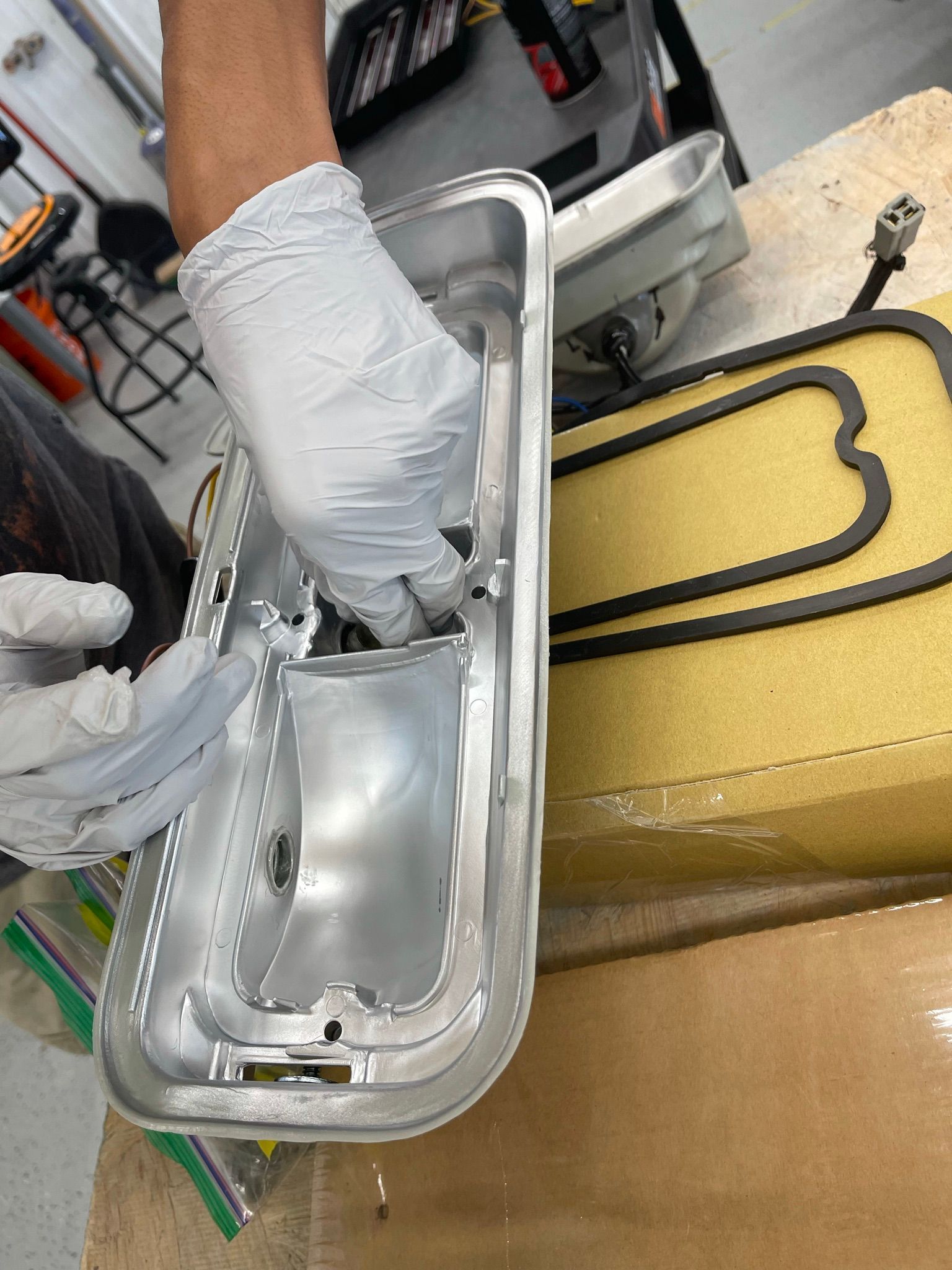 A person wearing white gloves is working on a piece of metal.