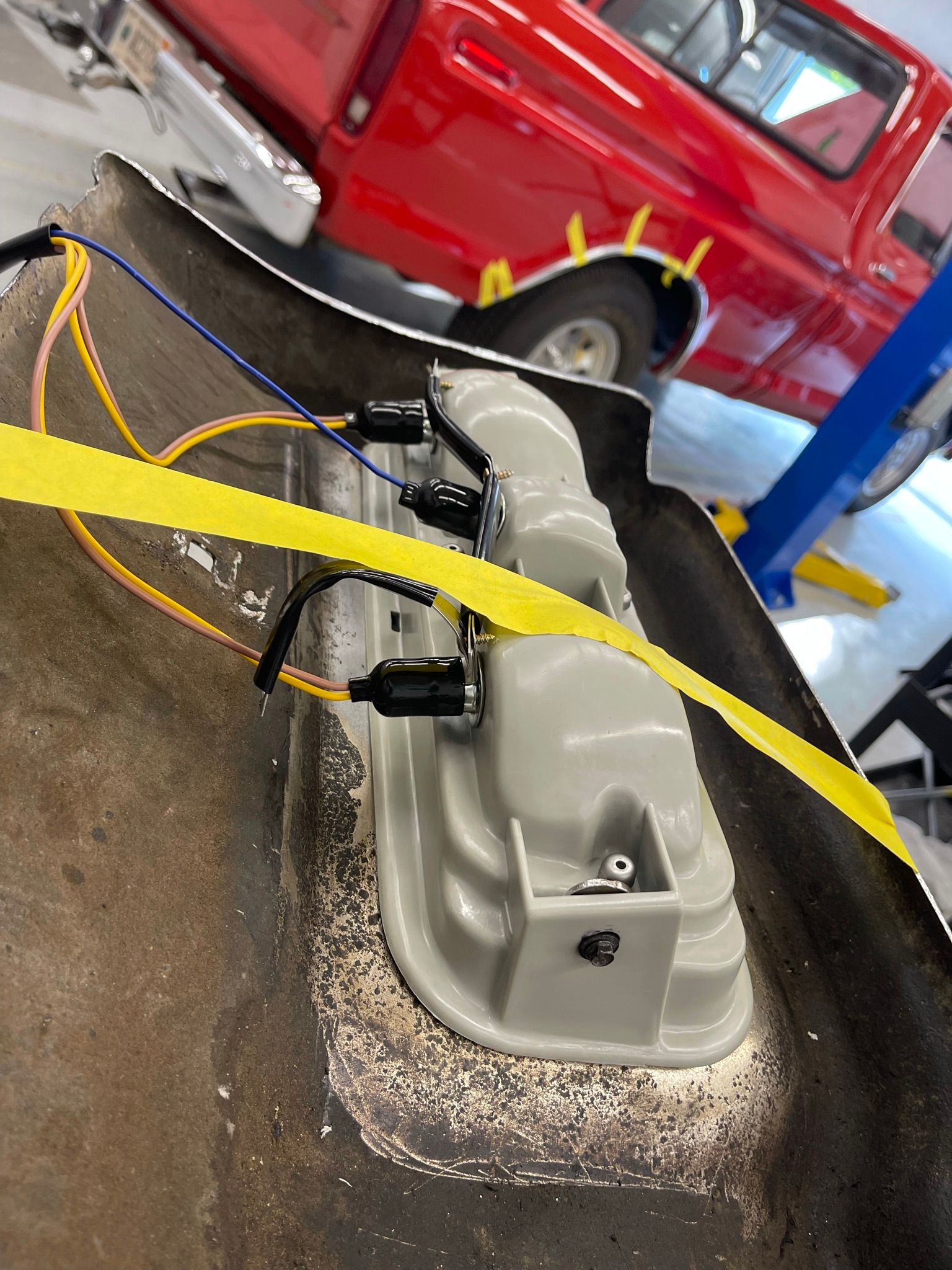 A red truck is parked in a garage next to a yellow tape.