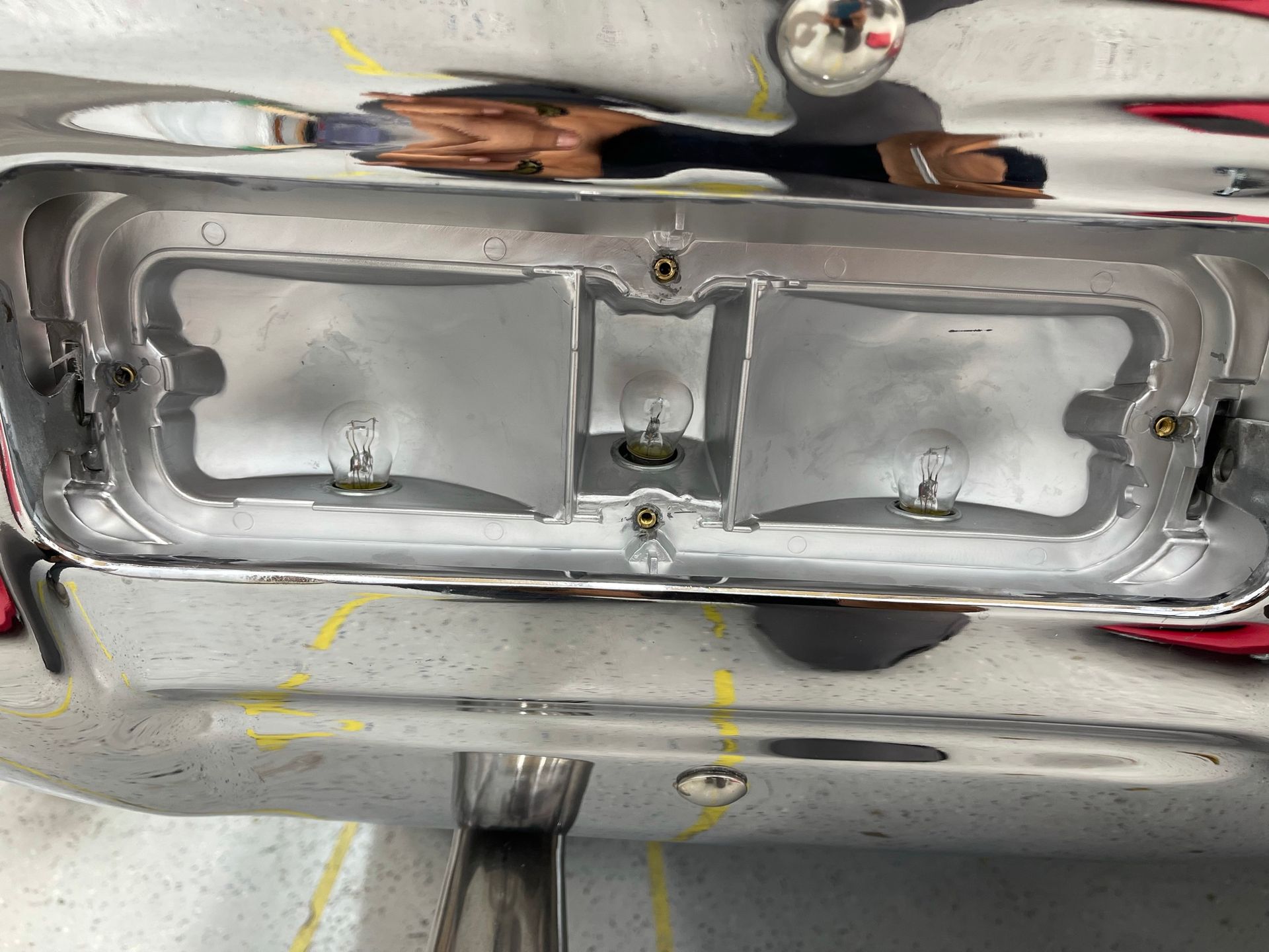 A close up of a chrome bumper with a reflection of a person in it.