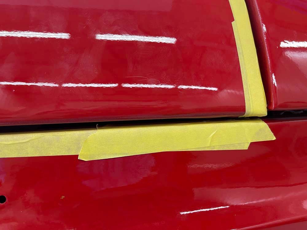 A close up of a red car with yellow tape on it.