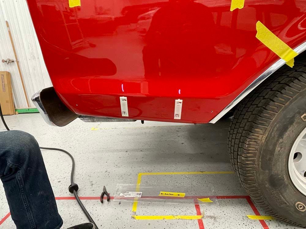 A person is working on a red car in a garage.