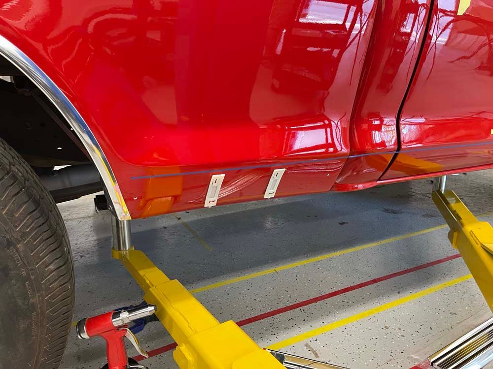 A red truck is sitting on a yellow lift in a garage.
