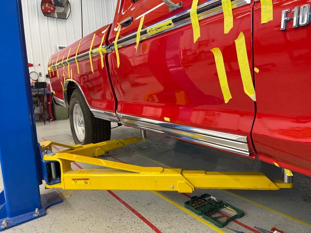 A red truck is sitting on a yellow lift in a garage.