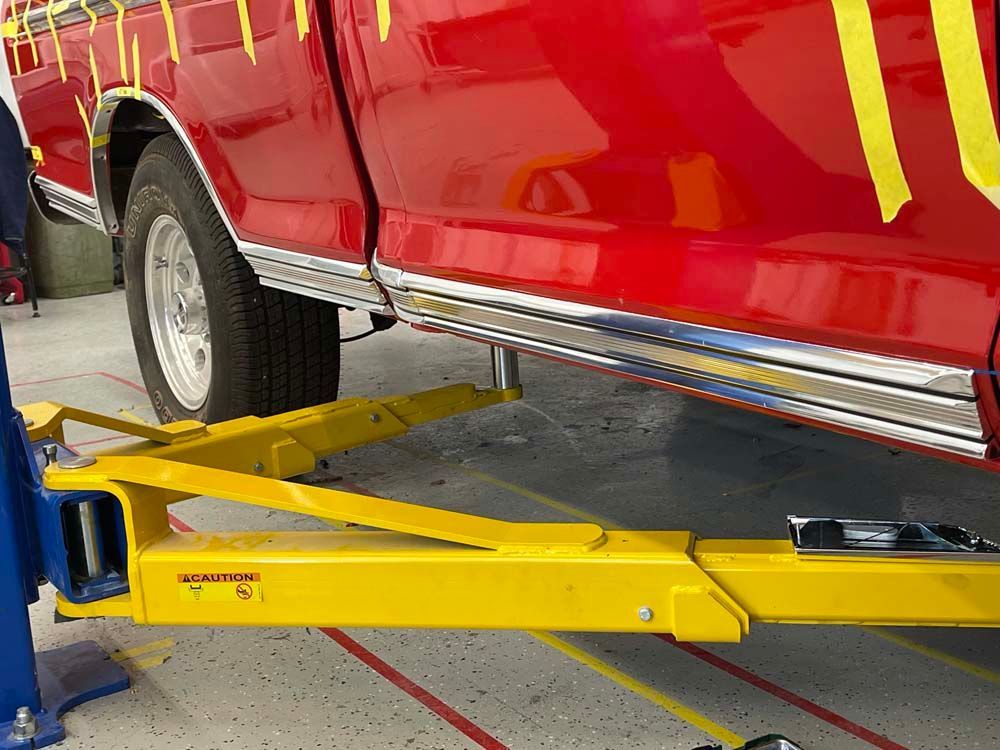 A red truck is sitting on top of a yellow lift.